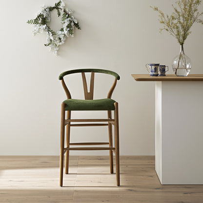 Tabouret de bar rembourré Hansel, velours vert mousse et cadre en noyer clair